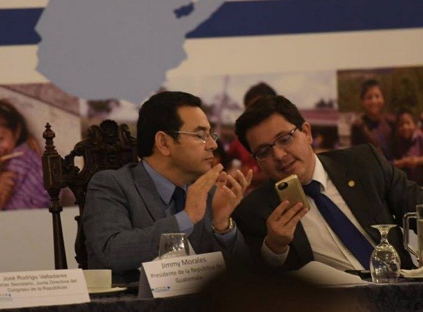 El presidente Jimmy Morales y el ministro de Finanzas, Julio Héctor Estrada conversan durante la presentación del presupuesto.