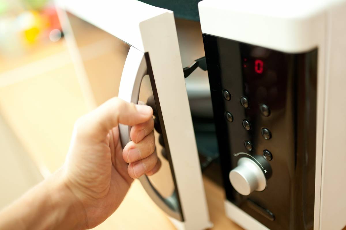 Hand of person opening a microwave oven