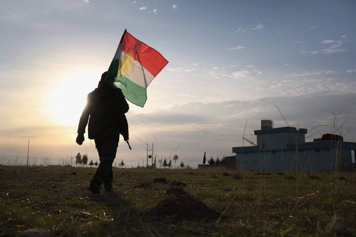 Un soldado peshmerga lleva la bandera de Kurdistán después de luchar contra el Estado Islámico.