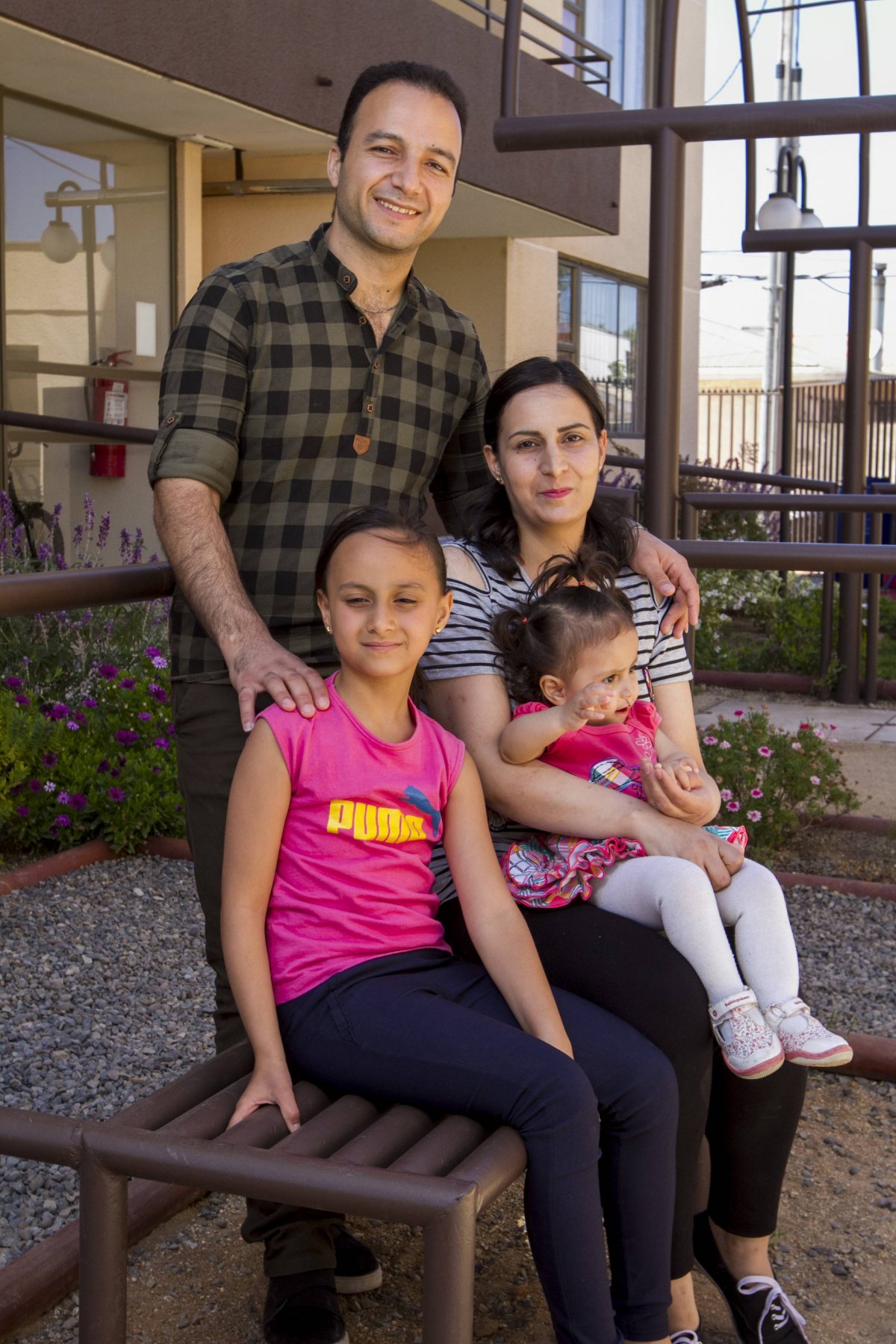 La familia Balshehawi en el living de su casa: el padre, Nabil, junto a la hija más pequeña, Basil. Abajo, Juli, la hija mayor, junto a su madre, Roa
