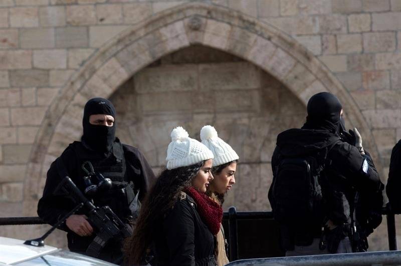 Dos muchachas palestinas pasan delante de dos policías israelíes que vigilan la Puerta de Damasco, en el casco viejo de Jerusalén