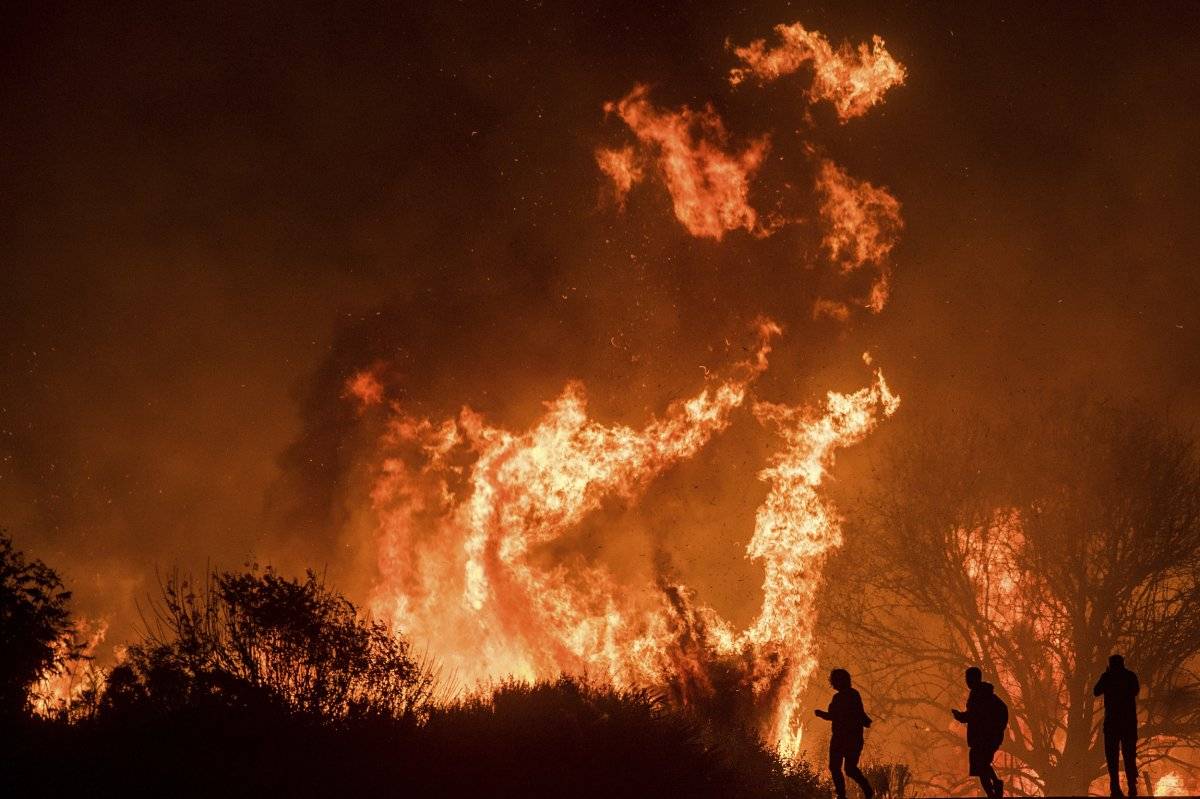 Varios conductores en la carretera 101 observan llamas del incendio Thomas que saltan sobre el camino al norte de Ventura, California, el miércoles 6 de diciembre de 2017. (AP Foto/Noah Berger)