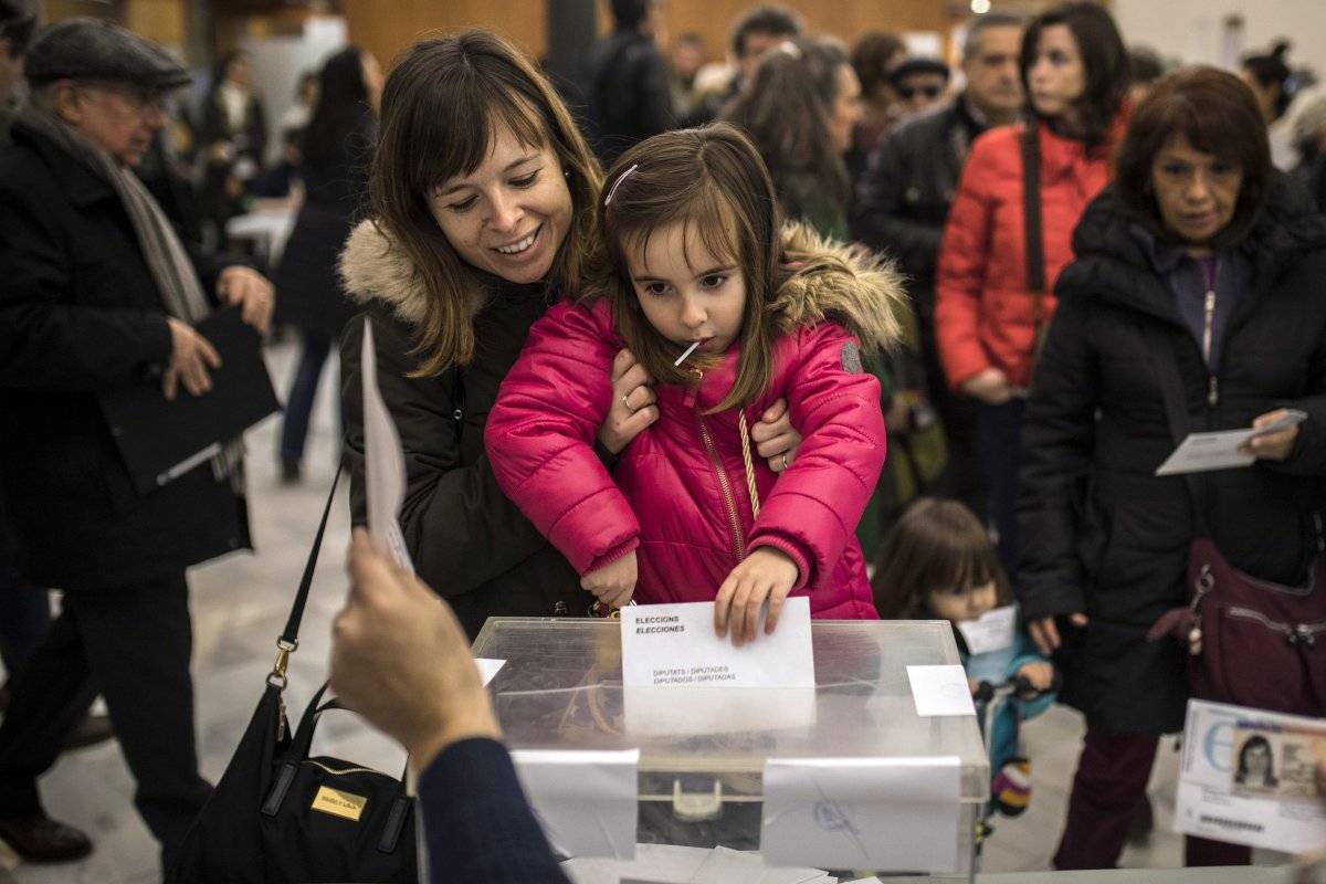 Una mujer sostiene a su hija para que meta su papeleta en la urna en un centro electoral durante las elecciones regionales de Cataluña, en Barcelona, España, el jueves 21 de diciembre de 2017. (Foto: AP/Santi Palacios)