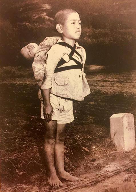 Foto mostra bebê morto sendo levado por irmão após ataque nuclea