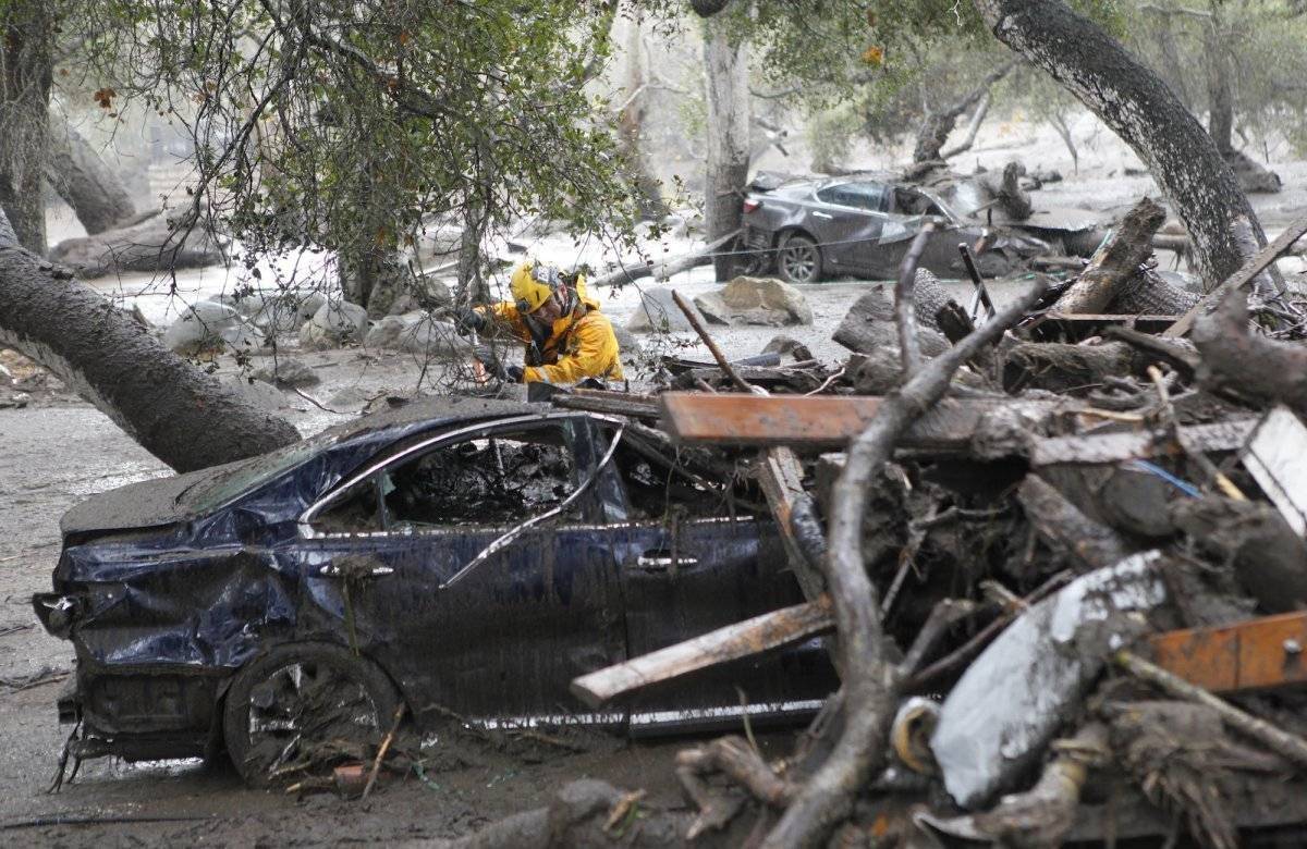 Un miembro del equipo de búsqueda y rescate de Long Beach busca sobrevivientes dentro de un automóvil en Montecito, California, el martes 9 de enero de 2018. (Daniel Dreifuss)