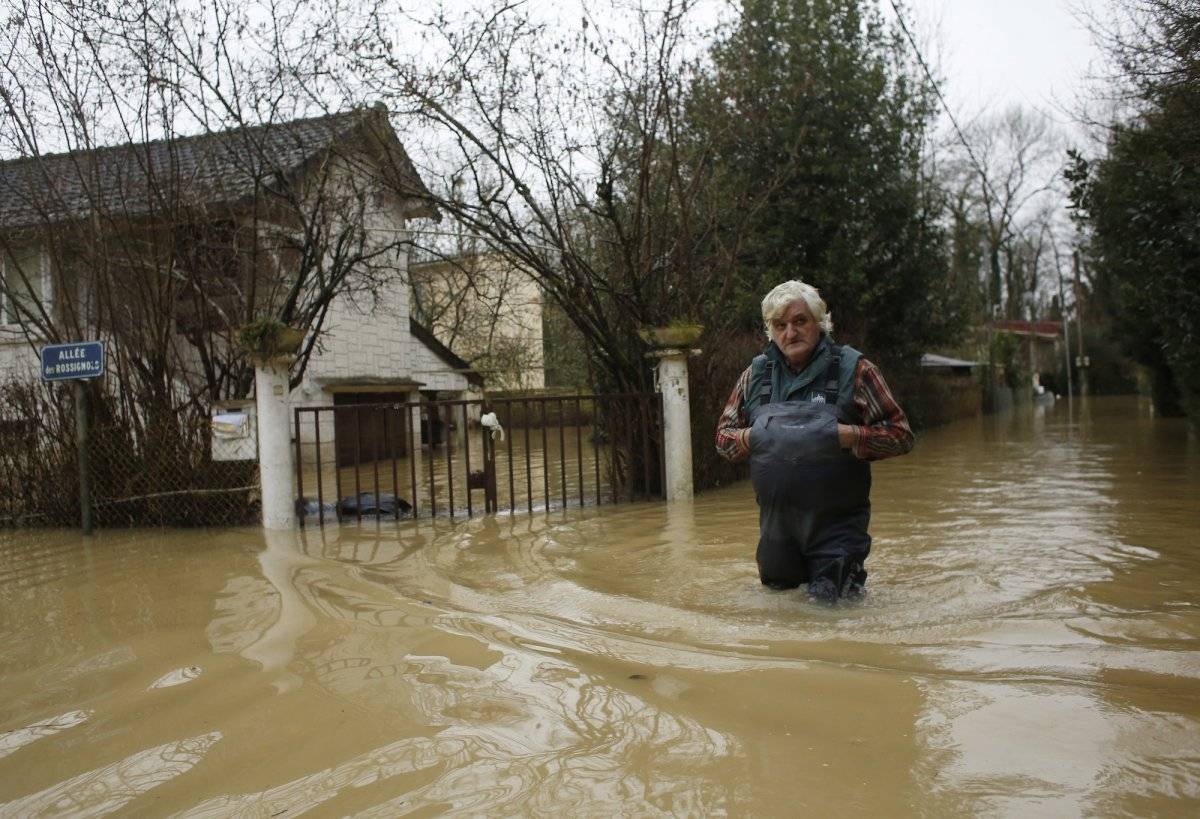 Una persona camina en una calle inundada en el este de París el jueves 25 de enero de 2018. (AP Foto/Thibault Camus)