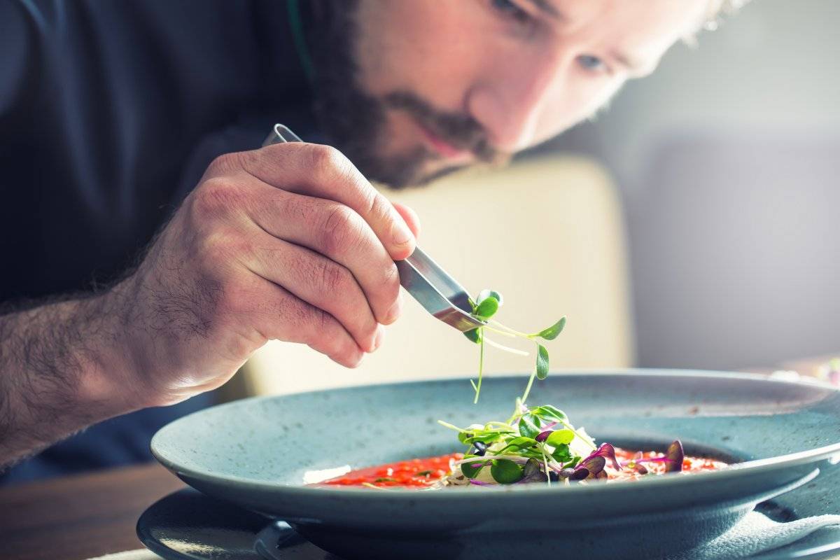 Chef in hotel restaurant kitchen cooking, only hands.Preparing tomato soup