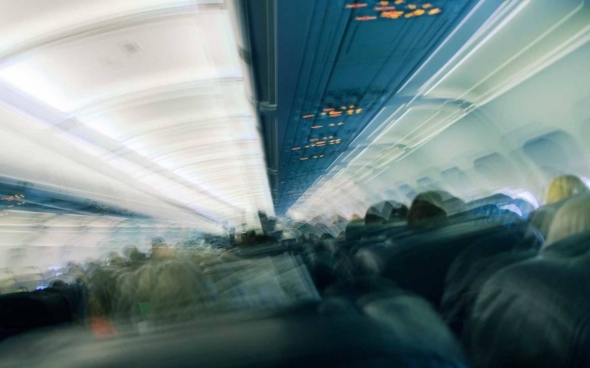Seated passengers in aeroplane cabin, rear view (multiple exposure)
