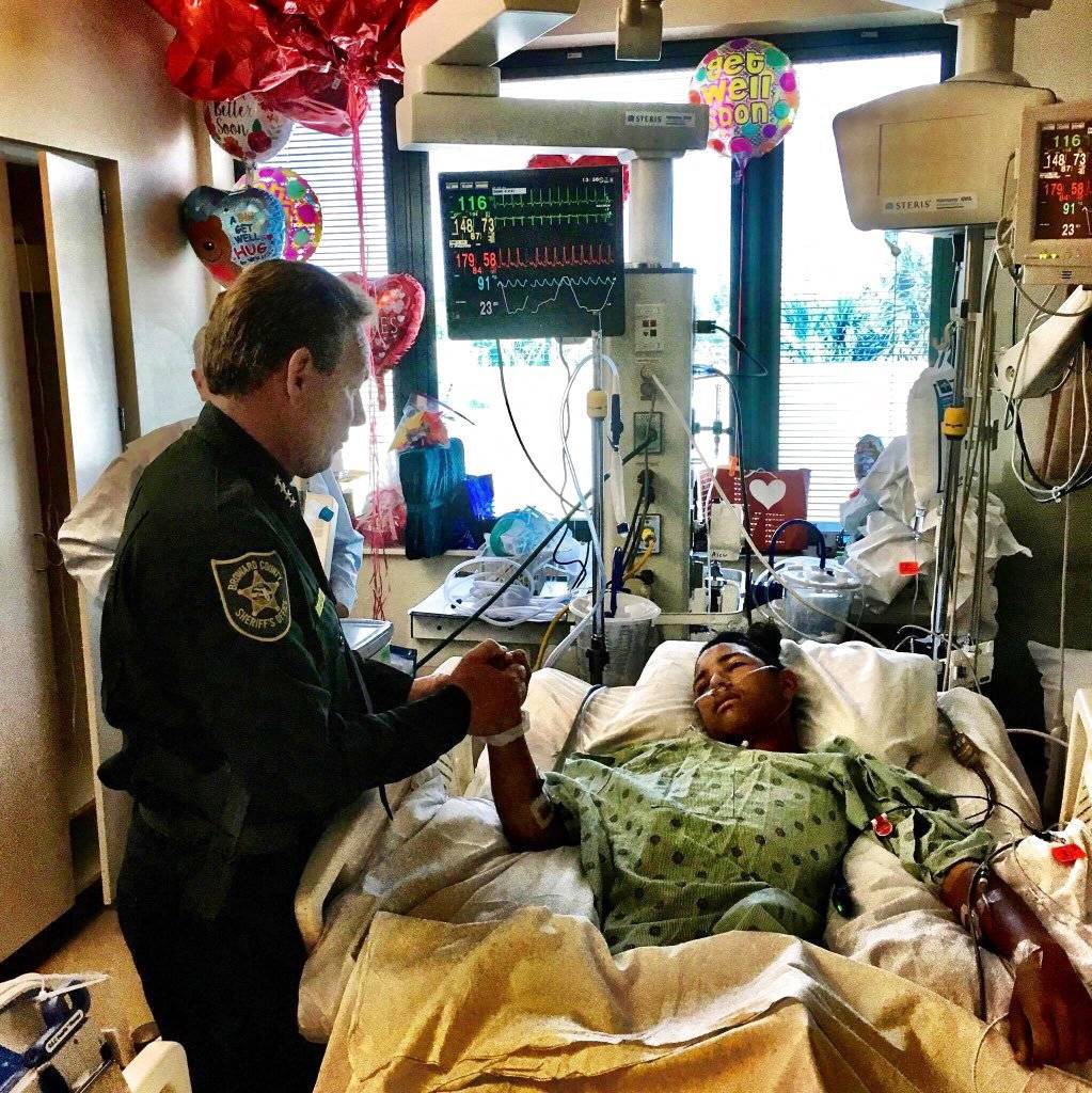 En esta foto del 18 de febrero de 2018, el jefe de policía del condado Broward, Scott Israel, sostiene la mano de Anthony Borges, un estudiante venezolano herido en el tiroteo del 14 de febrero en la escuela secundaria Stoneman Douglas. (Broward County Sh