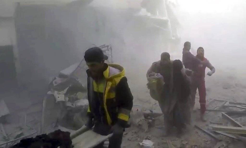 En esta imagen, tomada de un video publicado el 24 de febrero de 2018 por el grupo Defensa Civil Siria, también conocido como Cascos Blancos, muestra a voluntarios de la formación ayudando a residentes durante ataques aéreos y bombardeos de las fuerzas de