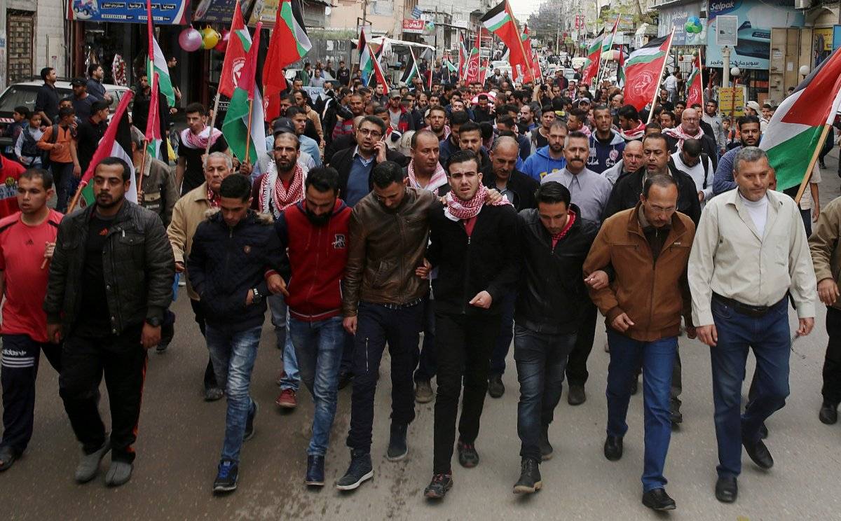 Los asistentes al entierro del periodista palestino Ahmed Abu Hussein, que murió tras recibir un disparo del ejército israelí cuando cubría las protestas en la frontera, muestran banderas palestinas durante el funeral celebrado en el campo de refugiados d