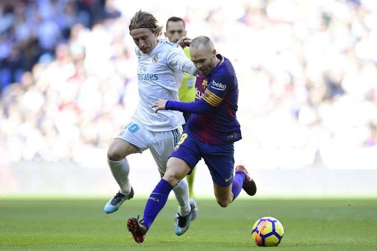 Rakitic trata de quitarle el balón a Iniesta