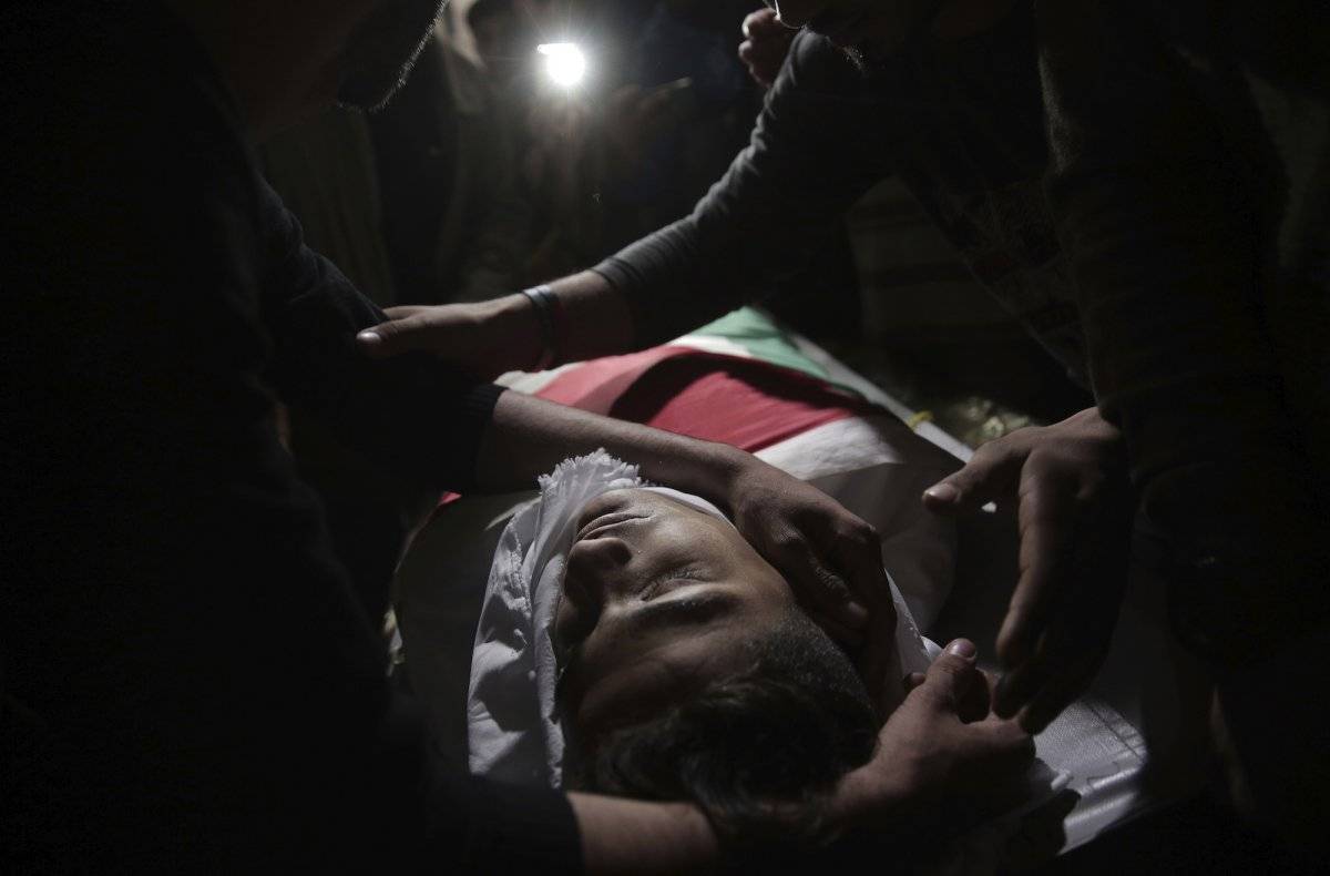 Familiares de Jamal Afaneh, un joven palestino de 15 años, velan su cuerpo en su casa durante su funeral, en el campo de refugiados de Rafah, en el sur de la Franja de Gaza, el 13 de mayo de 2018. Afaneh falleció tras ser baleado por soldados israelíes du