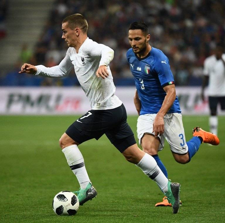 Antoine Griezmann conduce el balón ante la mirada de un italiano
