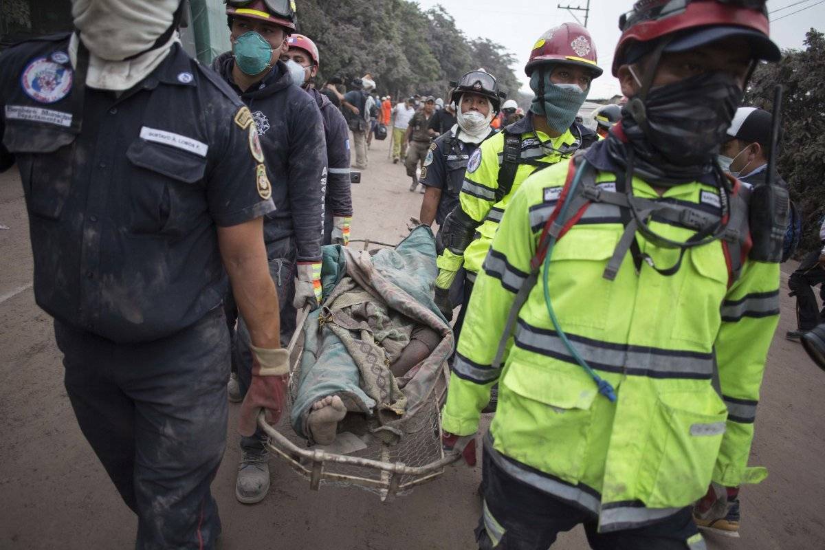 Los bomberos llevan un cuerpo recuperado cerca del Volcán de Fuego, en Escuintla, Guatemala, el lunes 4 de junio de 2018. Una ardiente erupción volcánica en el centro-sur de Guatemala envió lava a las comunidades rurales, matando al menos a 25 mientras lo