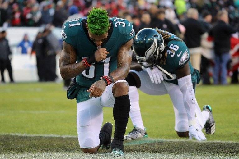Jugadores de los Eagles se arrodillan durante el himno