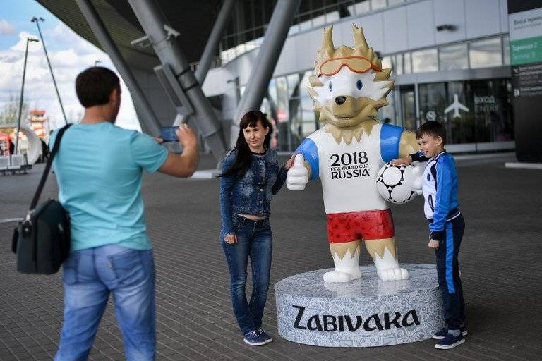 Dos aficionados posan junto a la mascota de Rusia 2018