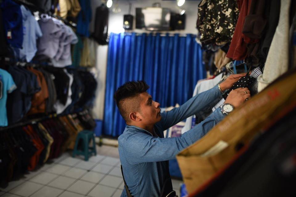 Lessther Avalos ordena la ropa en su tienda
