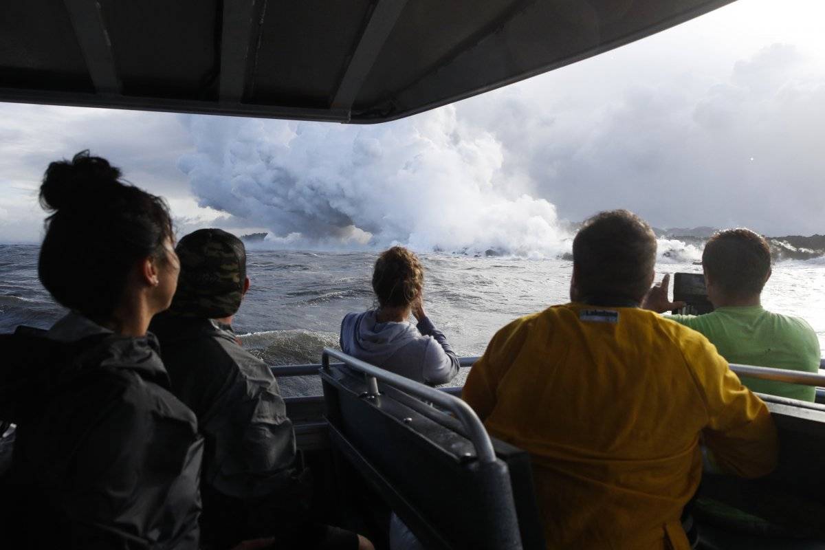 En esta fotografía del 20 de mayo de 2018 se muestra a un grupo de turistas que observan la lava que se interna en el océano, cerca de Pahoa, Hawai. (AP Foto/Jae C. Hong, Archivo)