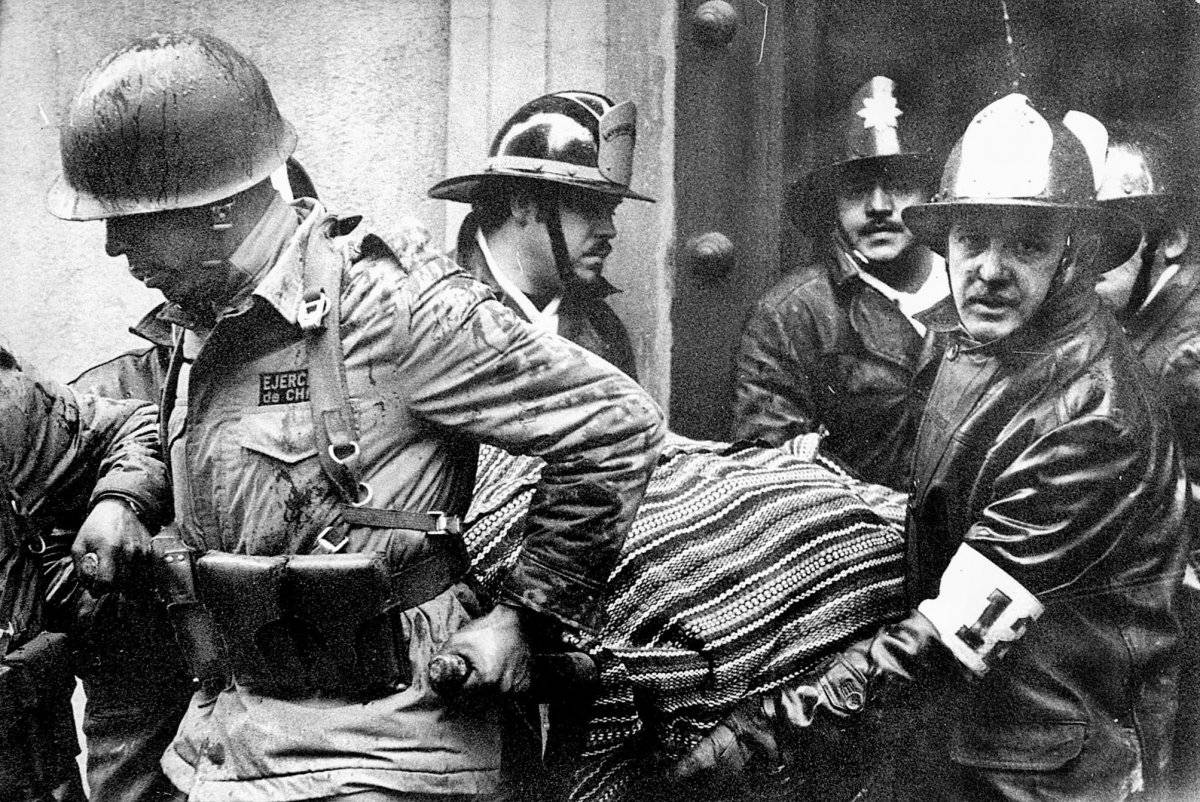 Soldados y bomberos portan el cuerpo del presidente Salvador Allende, envuelto en un poncho boliviano, del destruido palacio presidencial La Moneda después del golpe del 11 de septiembre de 1973 encabezado por el general Augusto Pinochet que puso fin al g