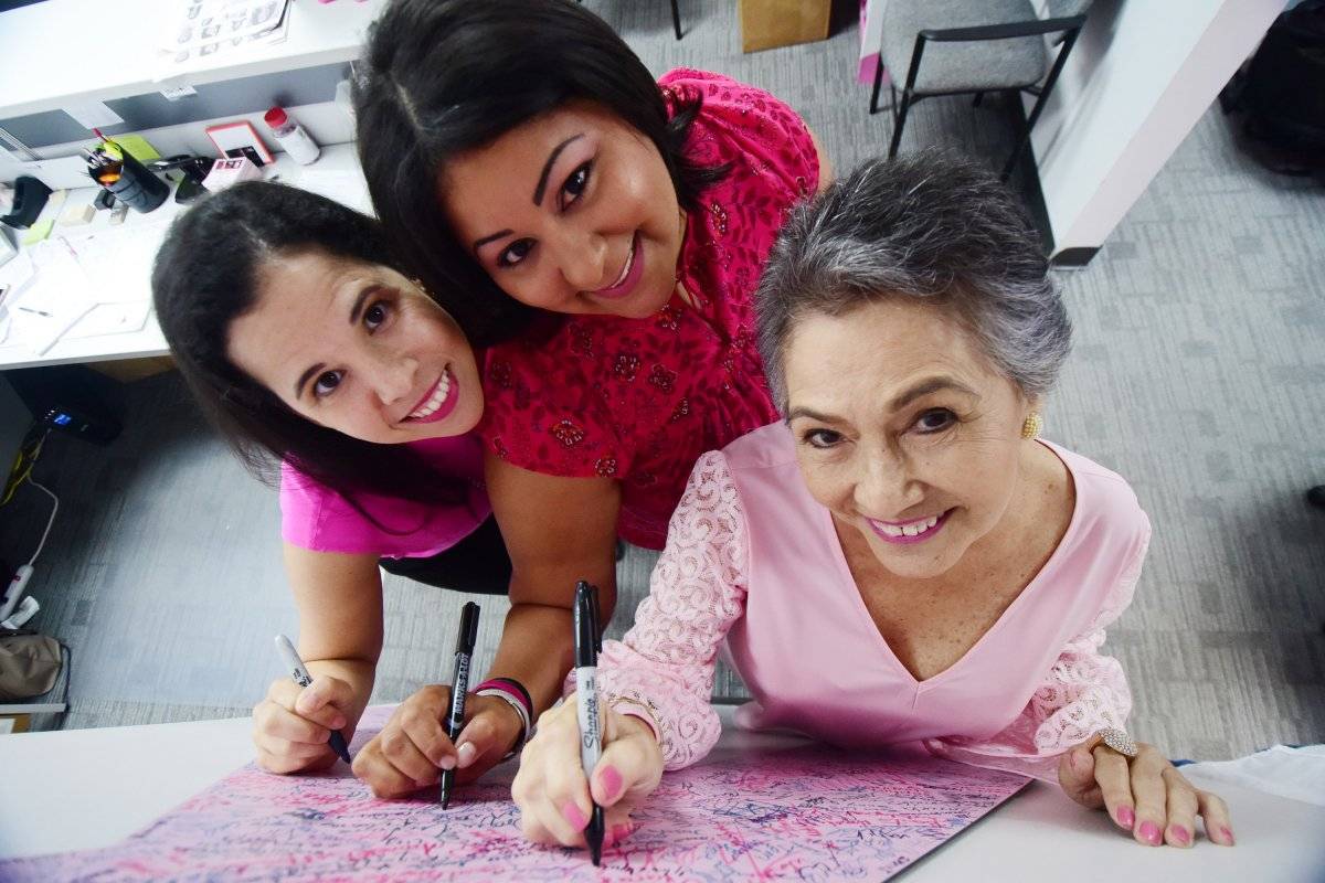 Marla, Judith y Gloria plasman su firma en el lazo rosado de la Fundación Susan G. Komen Puerto Rico. Foto: Dennis Jones