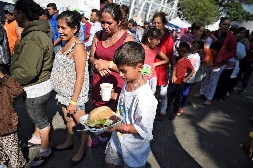 Familias migrantes hondureñas se alimentan en ciudad de México.