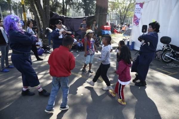 Una payasita entretiene a niños que son parte de la caravana migrante.