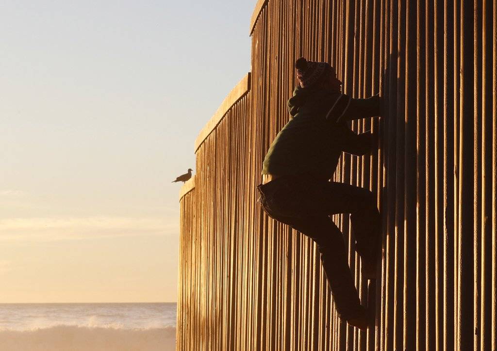 Migrantes en muro de EE. UU.