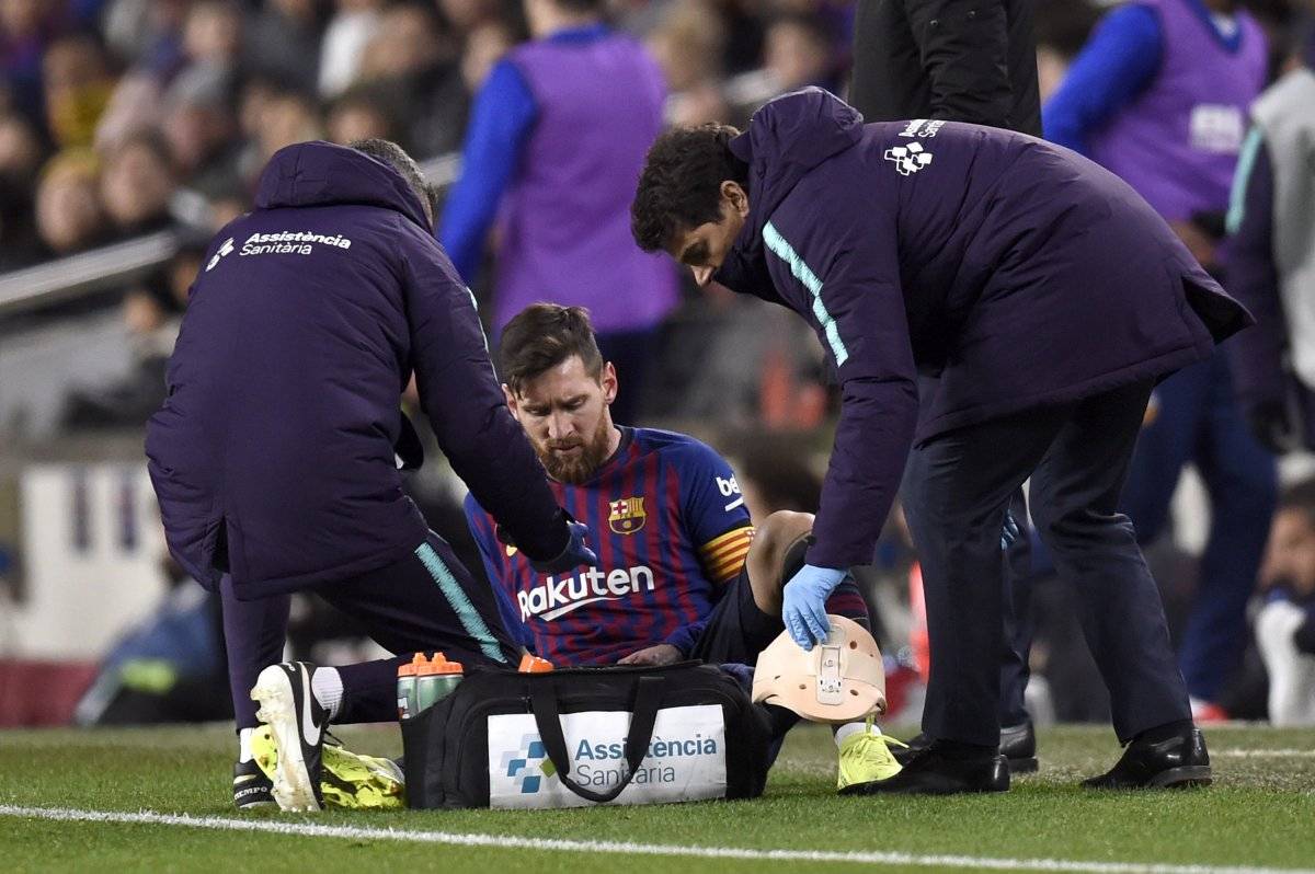 Lionel Messi es atendido por el cuerpo médico del Barcelona en el empate ante el Valencia del sábado pasado por liga española. / Getty Images