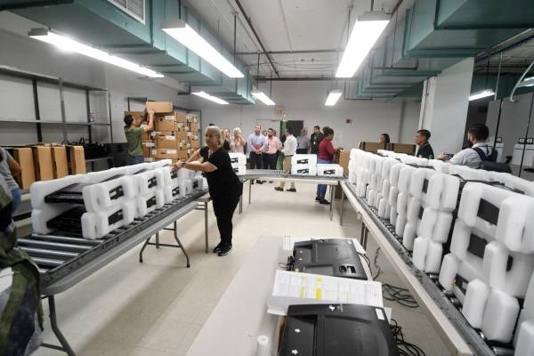 Empleados de la CEE trabajan en la fase uno y dos del proceso de mantenimiento de las máquinas de escrutinio electrónico. / Foto: Dennis Jones