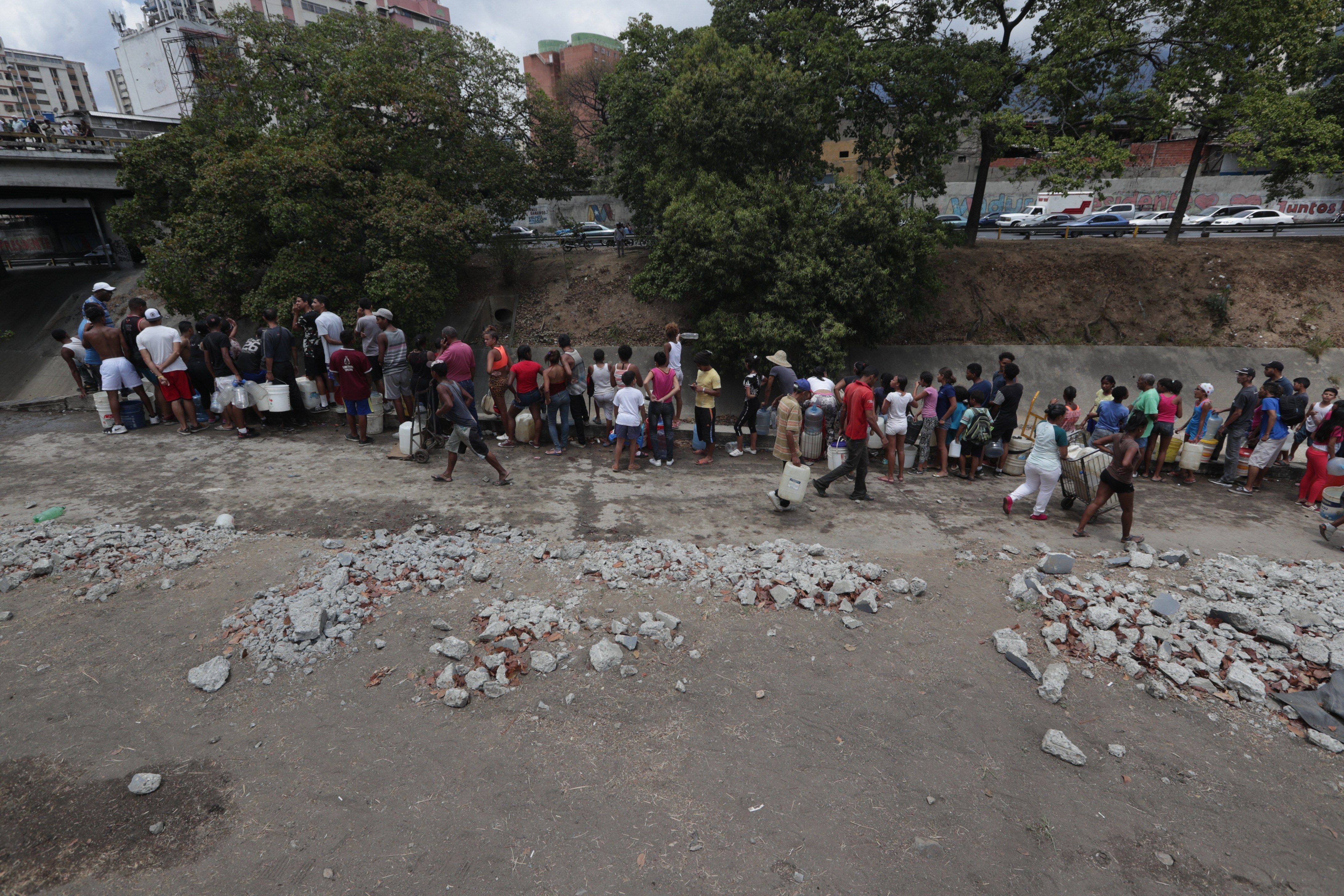 Caraqueños recogen agua en el Río Guaire debido a la escasez por apagón en Venezuela