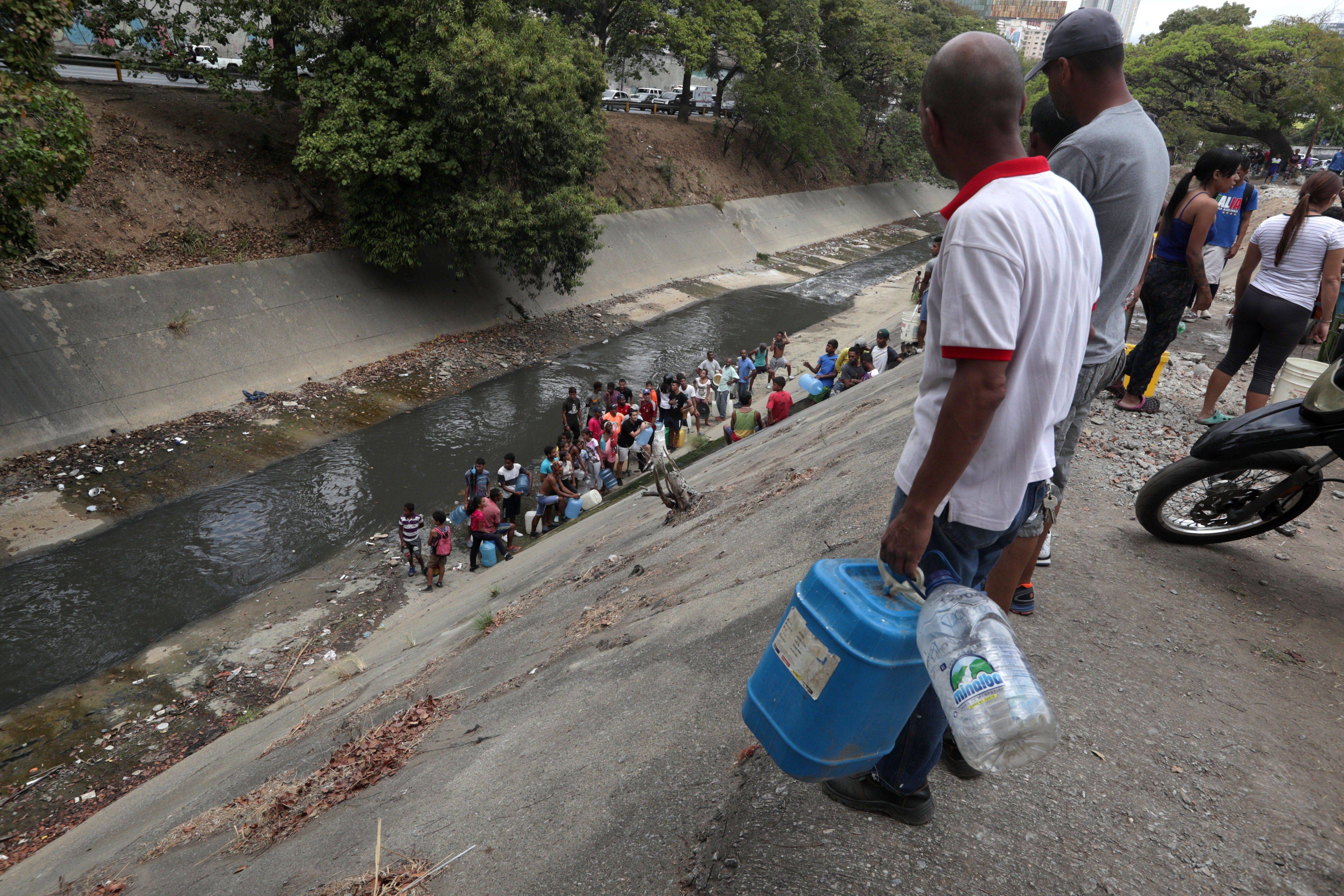 Caraqueños recogen agua en el Río Guaire debido a la escasez por apagón en Venezuela