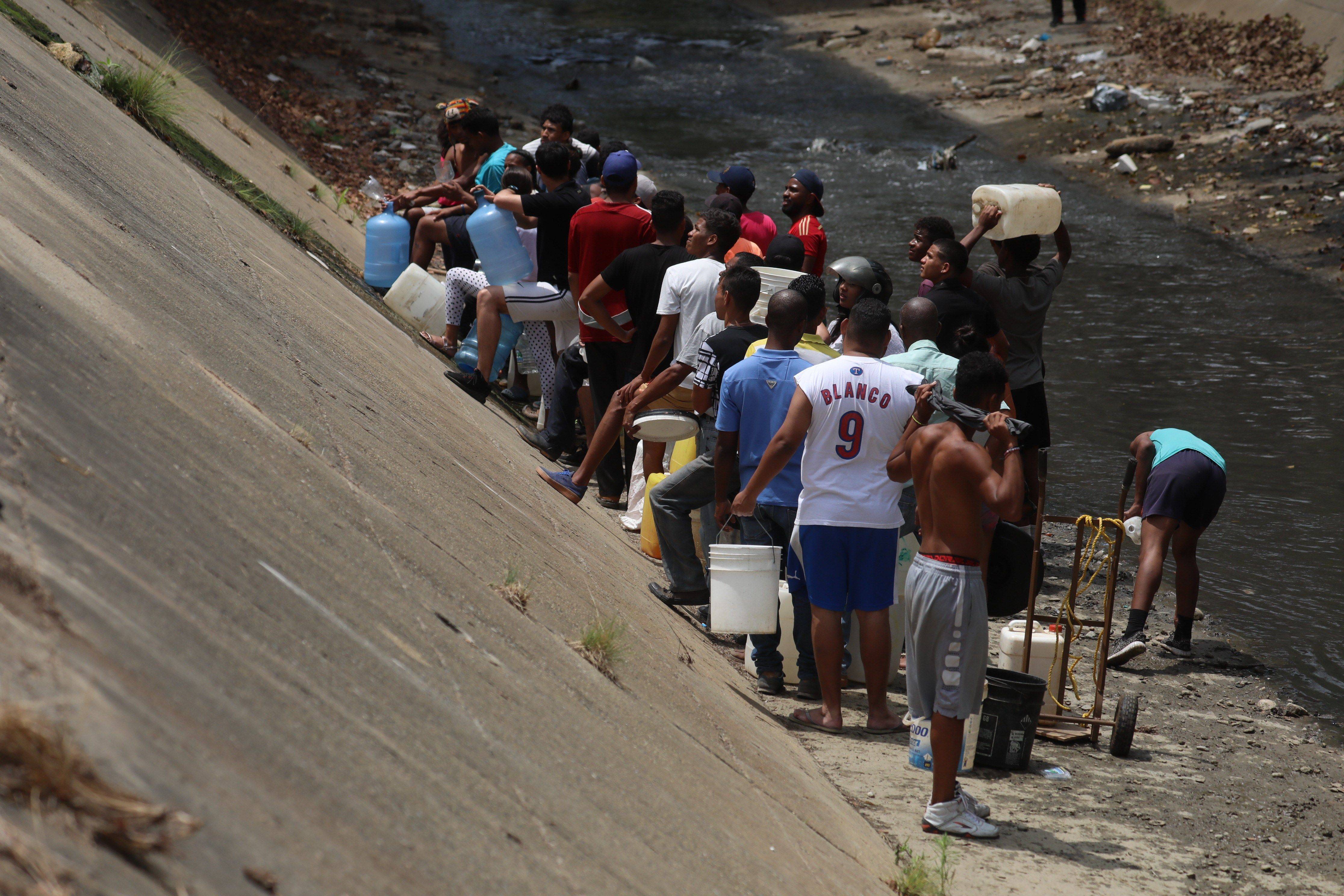 Caraqueños recogen agua en el Río Guaire debido a la escasez por apagón en Venezuela