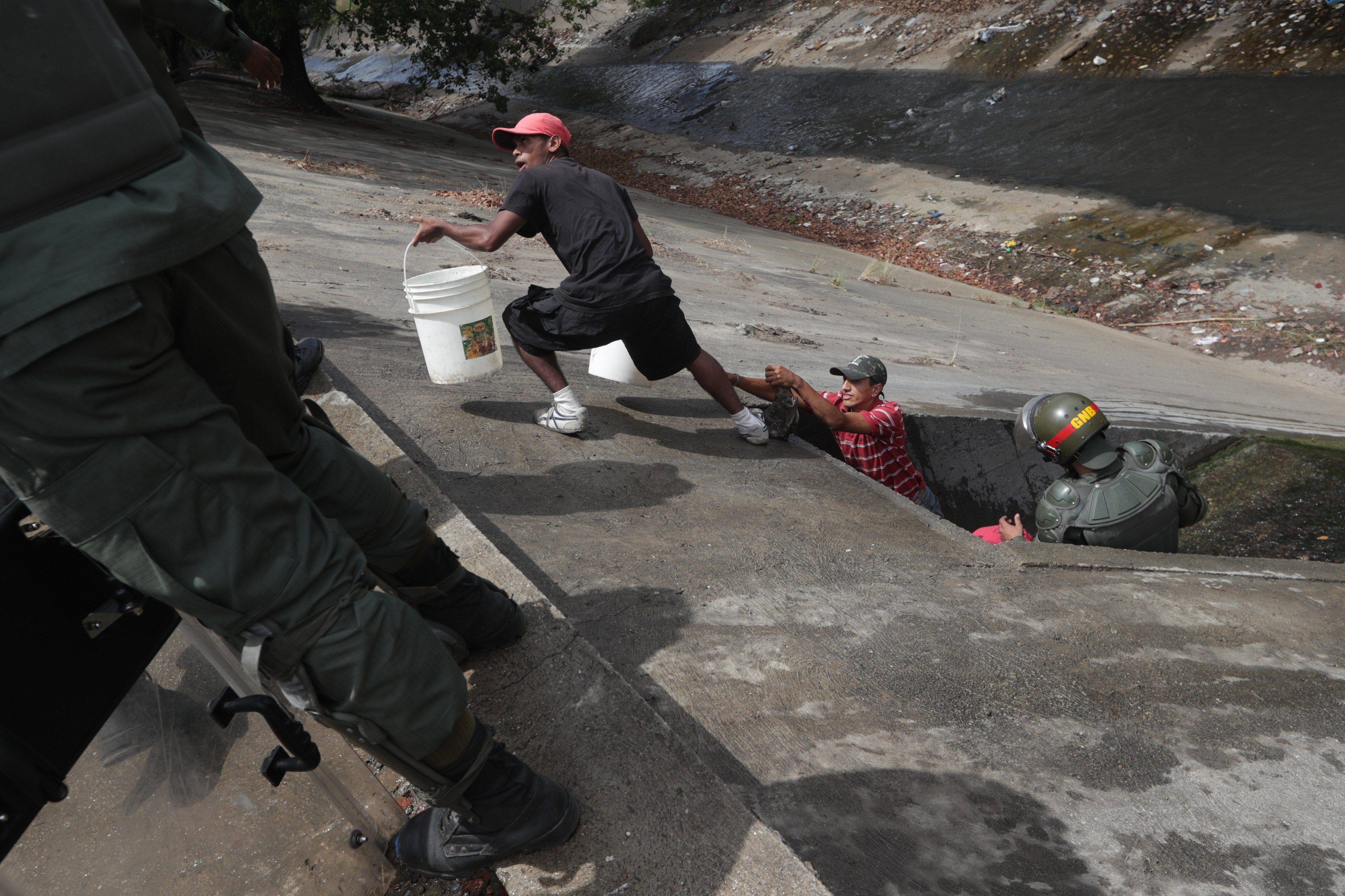 Caraqueños recogen agua en el Río Guaire debido a la escasez por apagón en Venezuela
