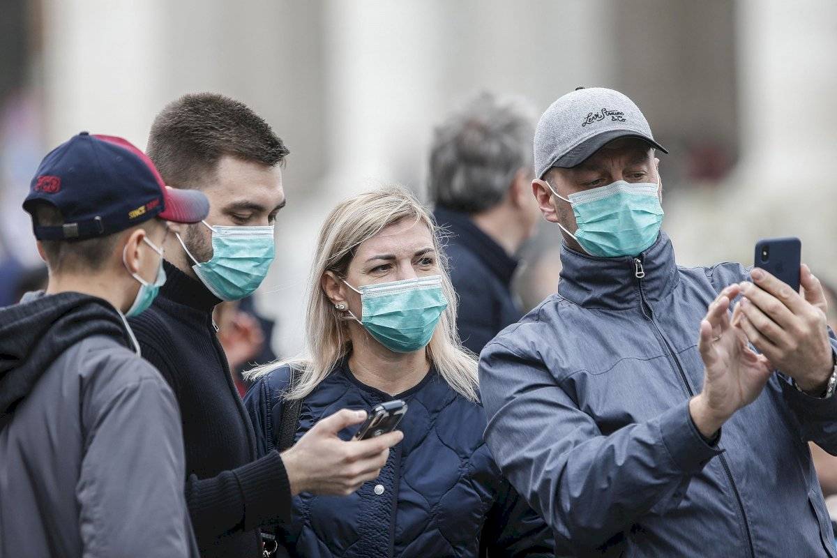 Varios asistentes llevan mascarillas para protegerse del coronavirus mientras asisten a la oración del Angelus, oficiada por el papa Francisco, en la plaza de San Pedro del Vaticano