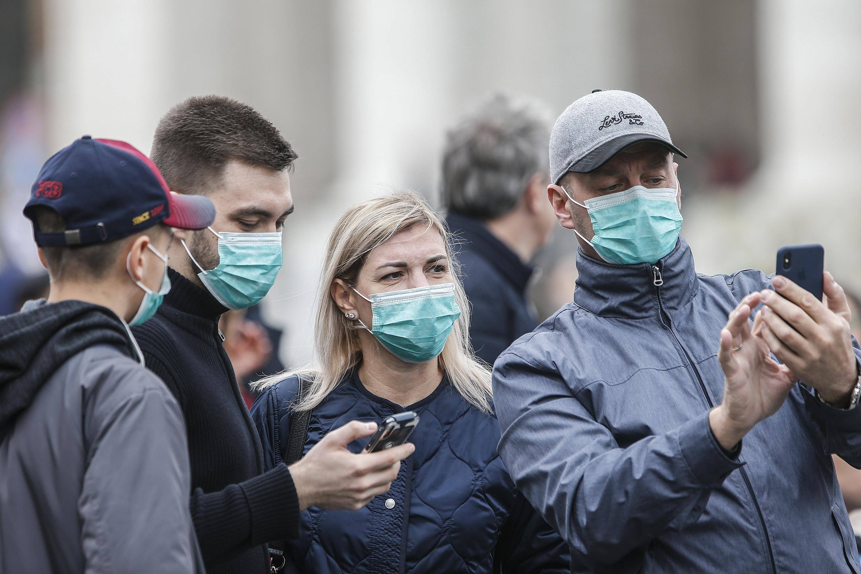 Varios asistentes llevan mascarillas para protegerse del coronavirus mientras asisten a la oración del Angelus, oficiada por el papa Francisco, en la plaza de San Pedro del Vaticano