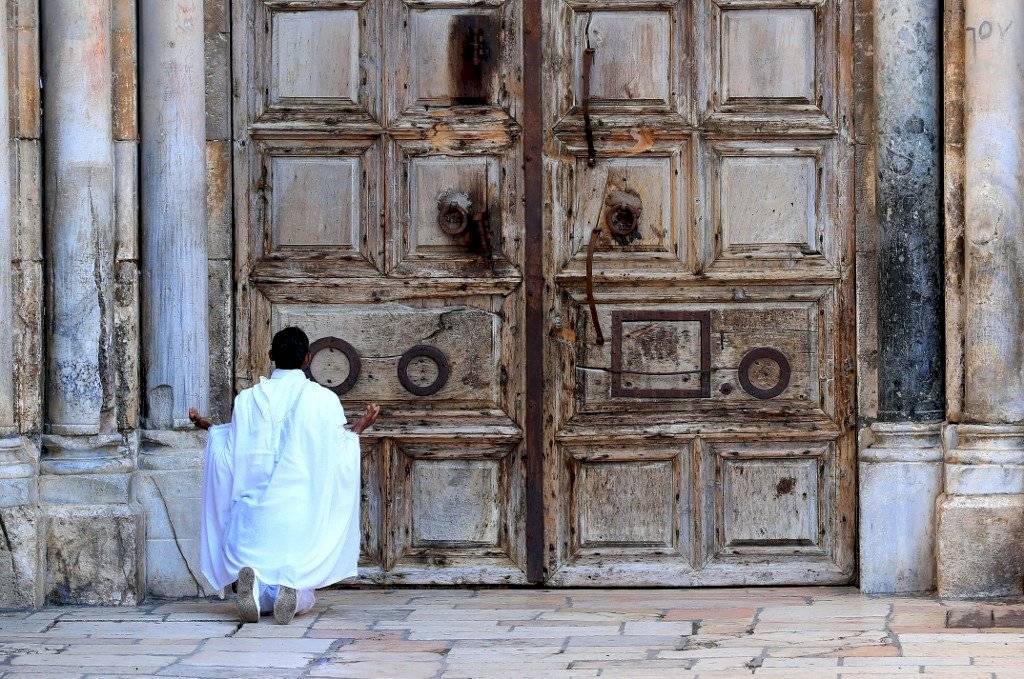 Un devoto cristiano reza frente a la puerta cerrada de la Iglesia del Santo Sepulcro