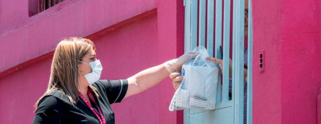 Una empleada del Fondo Costarricense de Seguridad Social (CCSS) usa una máscara facial mientras entrega medicamentos en los hogares de las personas