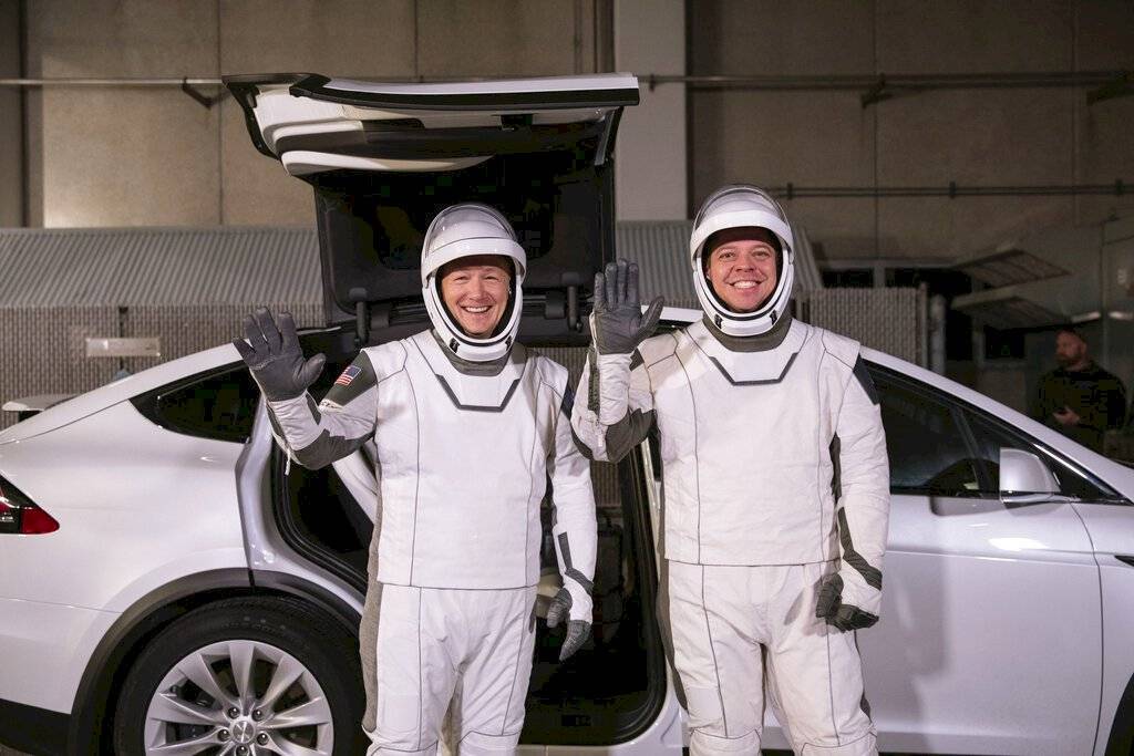 Los astronautas Doug Hurley (izquierda) y Robert Behnken posan frente al automóvil eléctrico Model X de Tesla durante un ensayo de lanzamiento en el Centro Espacial Kennedy, en Cabo Cañaveral, Florida.
