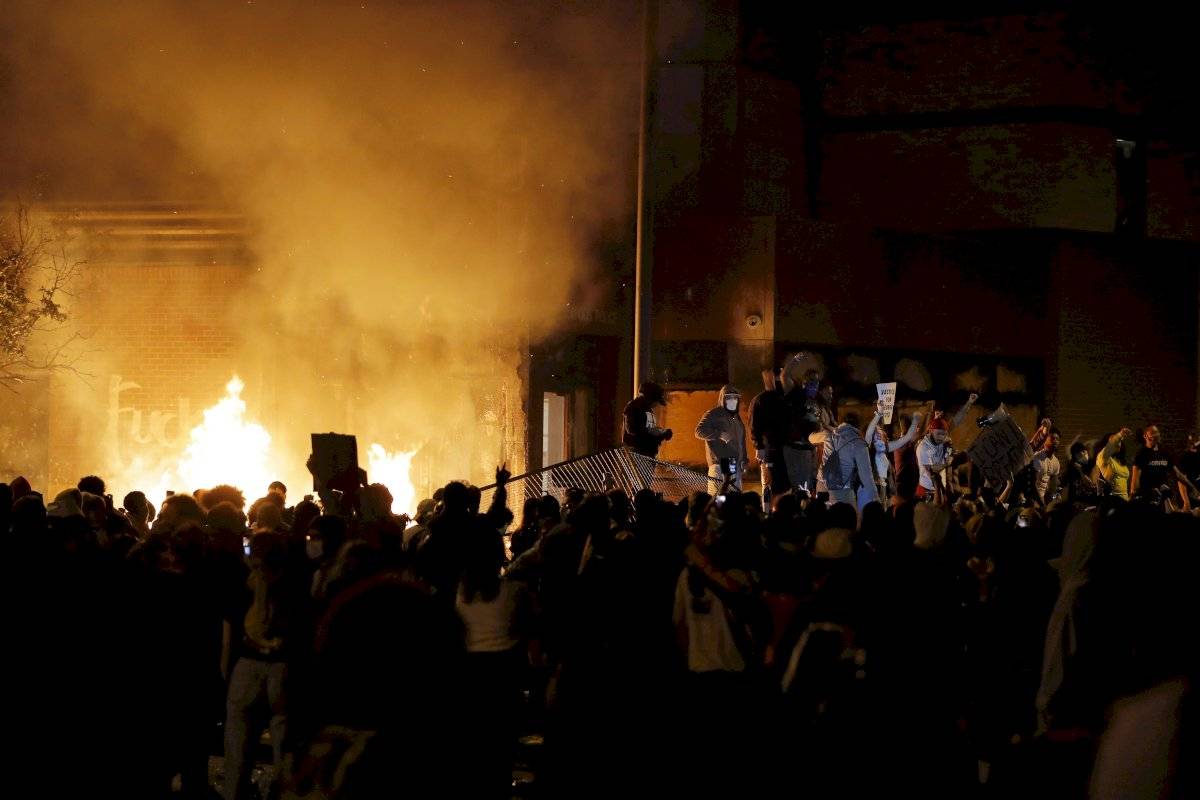 Manifestantes se concentran frente a una comisaría en llamas en Minneapolis, 28 de mayo de 2020.