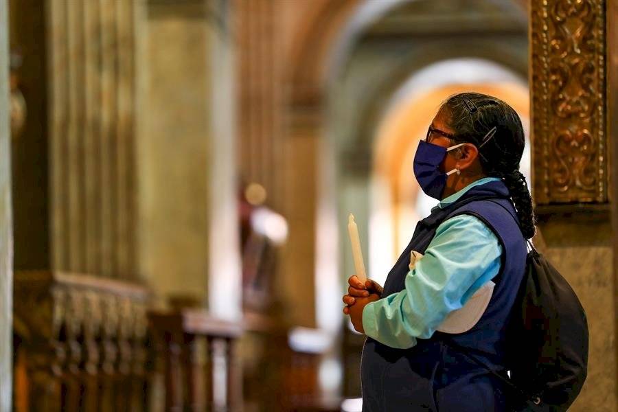 Una mujer con mascarilla reza este jueves, en la iglesia de Santo Domingo, en Quito