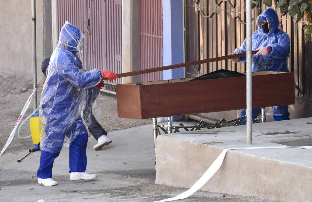 Trabajadores transportan un cadáver en Cochabamba / Foto: AP