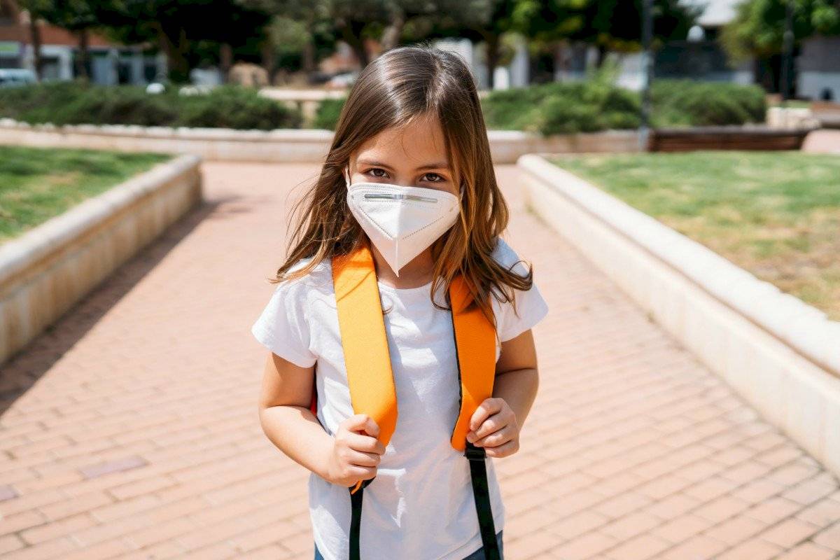 Retomada presencial das aulas exigirá uma readaptacão de toda comunidade escolar, professore,s colaboradores e alunos, como essa garota da imagem, que usa máscara e mochila nas costas.