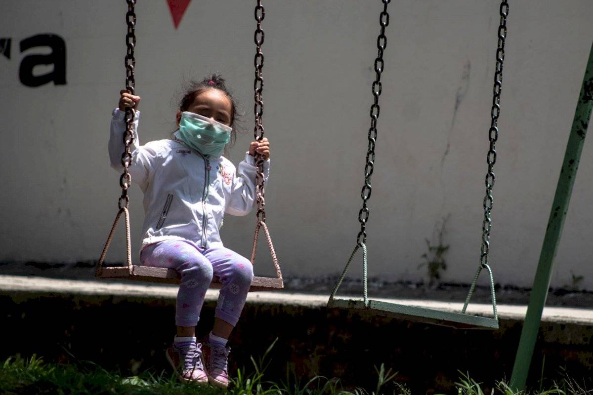 Niña en columpio con cubrebocas