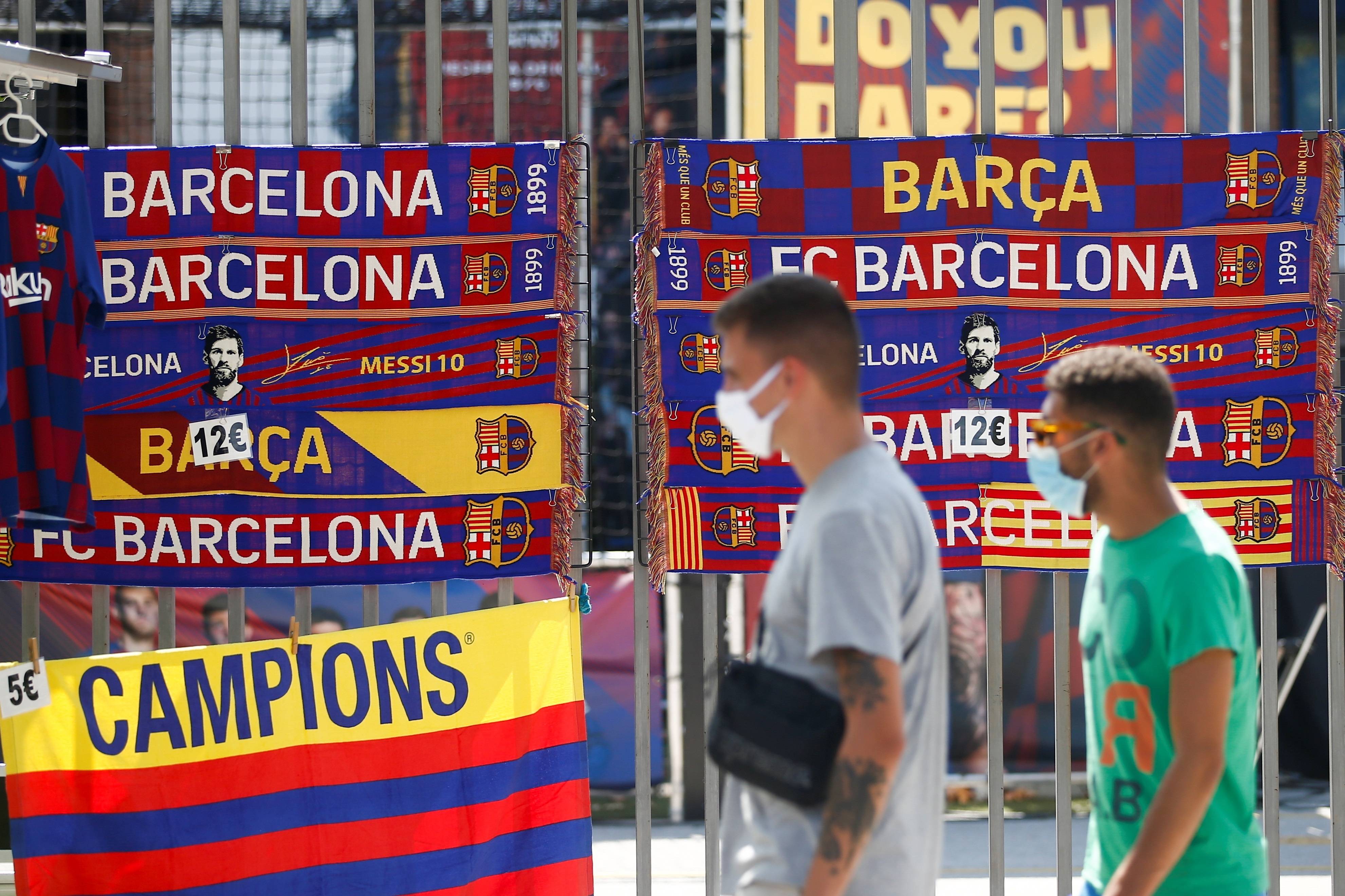 Unos jóvenes pasan ante una tienda de recuerdos cercana a las instalaciones del Camp Nou