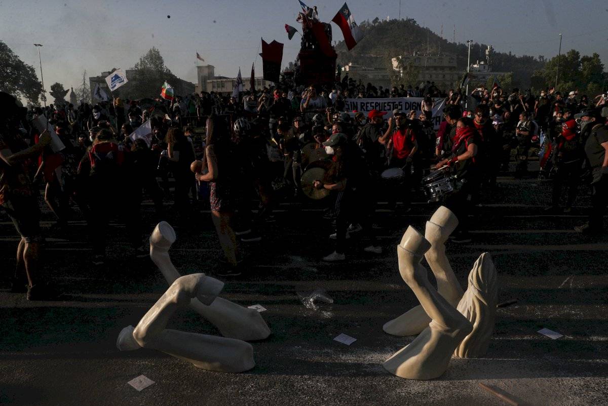 Manifestantes contra el gobierno protestan junto a la instalación de un caballo patas arriba del artista Maireni en Santiago de Chile el viernes 16 de octubre de 2020.