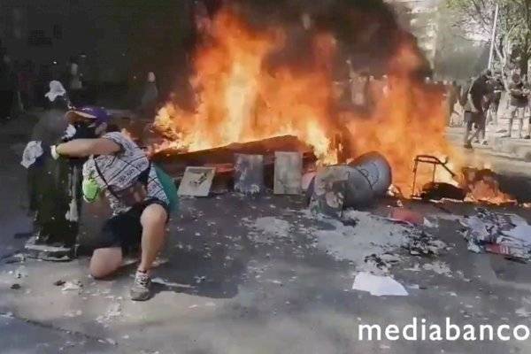 Manifestantes posan y se toman fotos junto a figuras religiosas calcinadas tras incendio de la Iglesia de Carabineros