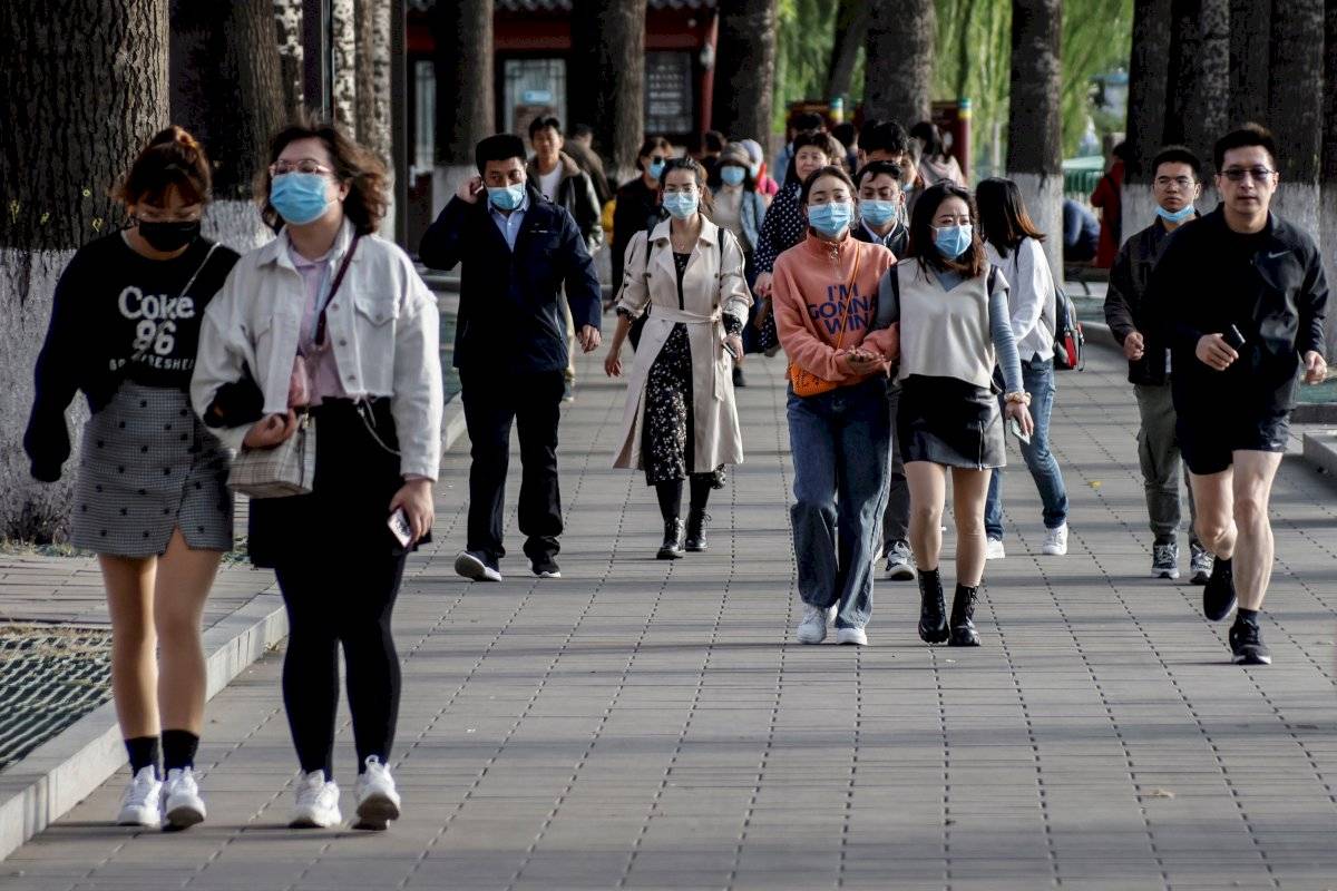 Personas con máscaras protectoras caminan por el parque Beihai en medio de la pandemia de coronavirus en Beijing