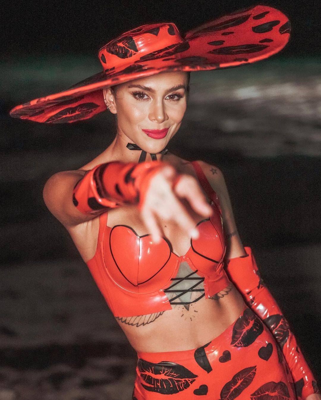 Greeicy causa sensación en un conjunto de leggings y mini top de látex rojo con enorme sombrero estampados con formas de besos greeicy