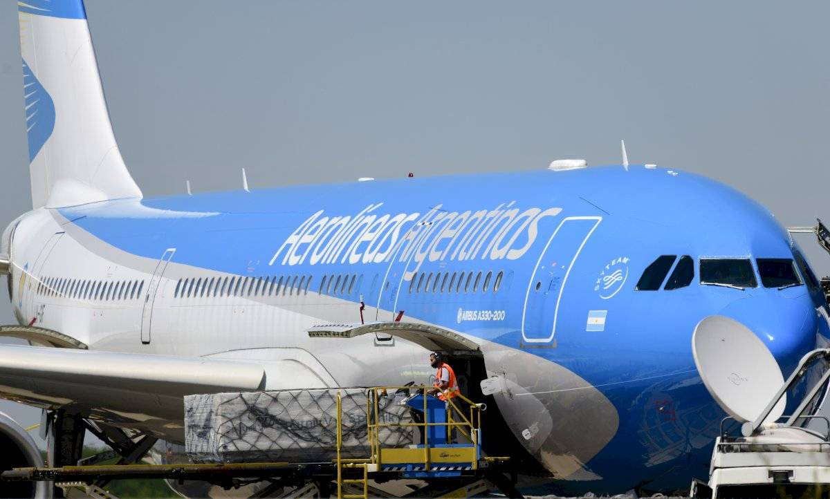 Trabajadores descargan el primer cargamento de la vacuna rusa Sputnik V contra COVID-19 desde un avión en el aeropuerto internacional de Buenos Aires